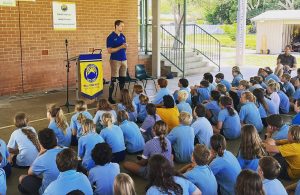 Australian Paralympian Curtis McGrath talking to a group of primary school students sitting on the ground in front of him,