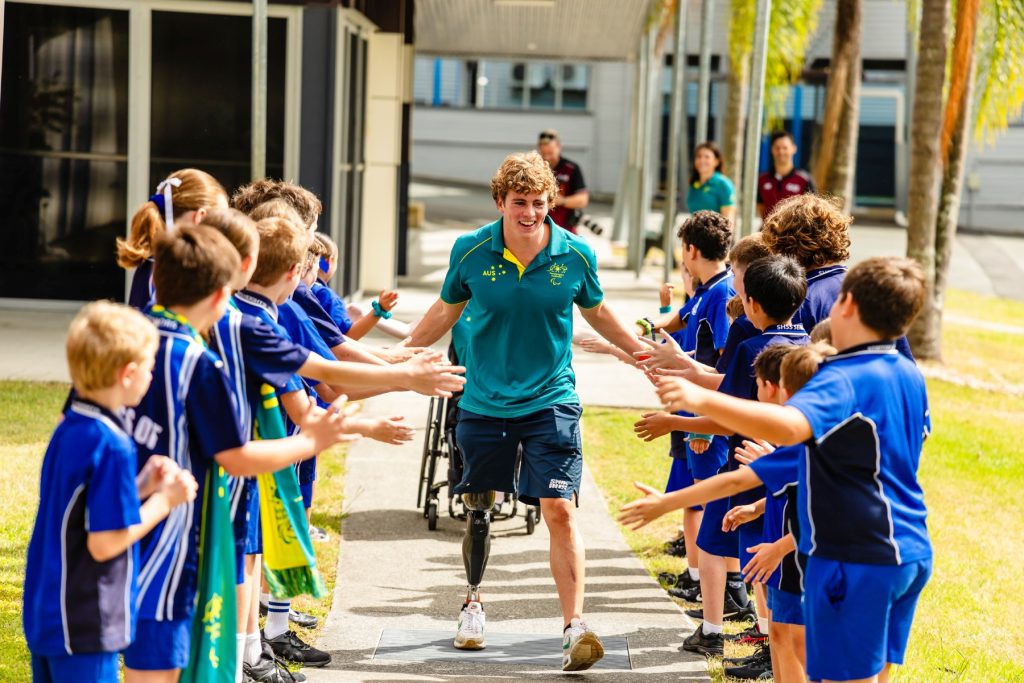 Lewis Bishop walking between a row  of school children giving high fives